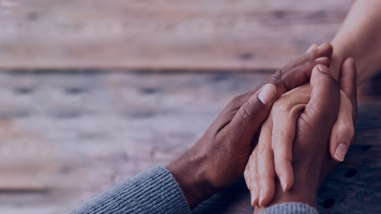 Two people clasping hands in care